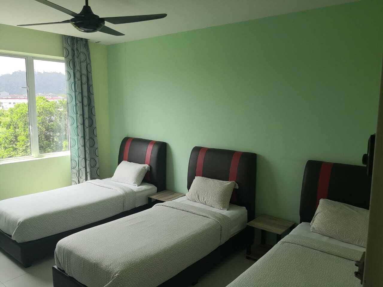 Una habitación con dos camas individuales, un ventilador de techo y una ventana con cortinas.