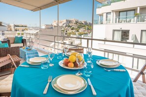 Une table dressée pour le dîner, offrant une vue sur le paysage urbain et les ruines antiques en arrière-plan.