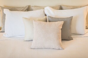 Un lit avec de nombreux oreillers aux motifs et aux textures variés.