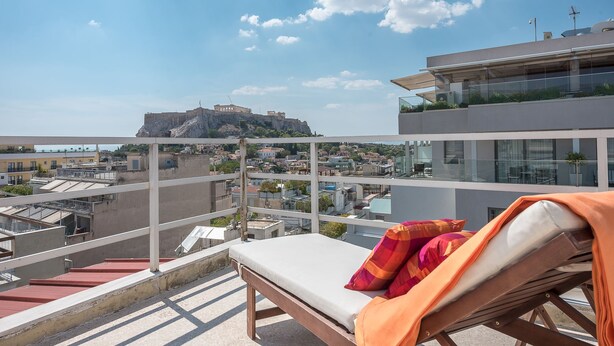 A balcony with a lounge chair and a view of a historic castle on a hill. - ALC Best View in Athens (Athens)
