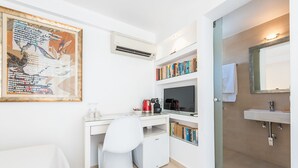 A modern bathroom with a white sink, mirror, and toilet. There is a bookshelf with books and a framed artwork on the wall. - ALC Best View in Athens (Athens)