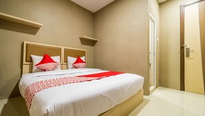 Una cama bien hecha con una colcha blanca y roja, dos almohadas y un cabecero de madera.
