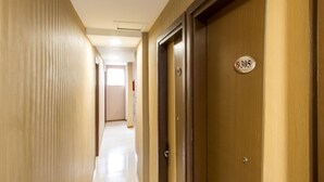 Pasillo de hotel con puertas de madera, un letrero con número y un extintor.