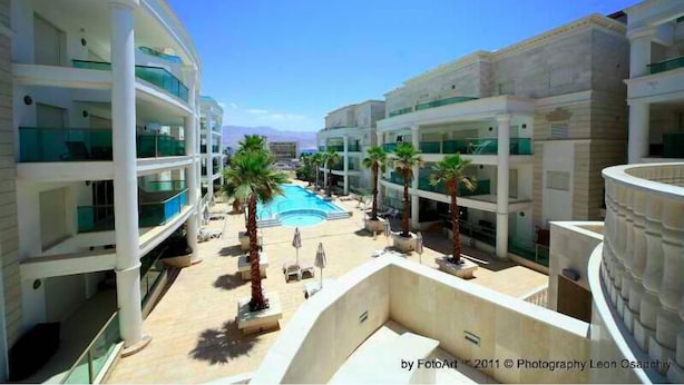 Un hotel con varios pisos, piscina y palmeras.