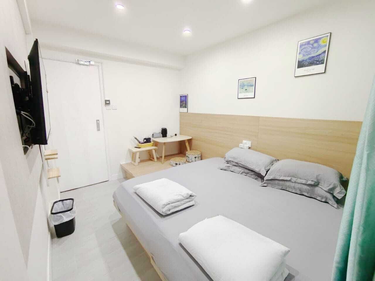 A hotel room with a bed, a desk, a chair, a TV, and a wall-mounted artwork.