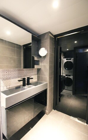 A modern bathroom with a large mirror, a double sink, and a toilet visible through a glass partition. - The Nap Tsim Sha Tsui (Kowloon)