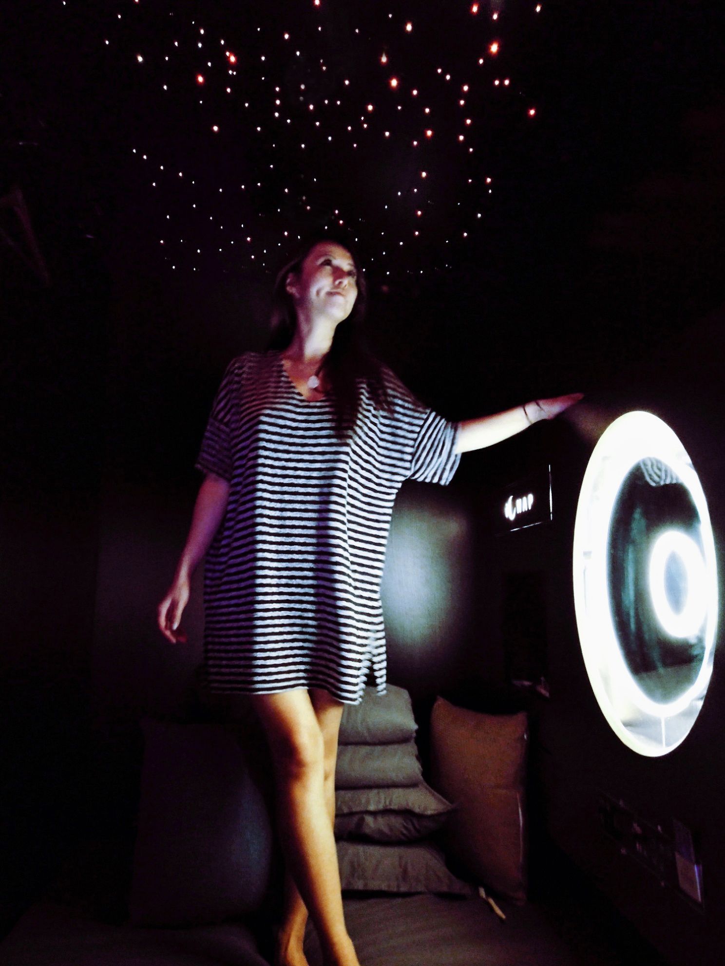 A person standing in a dimly lit room with a large circular light fixture.