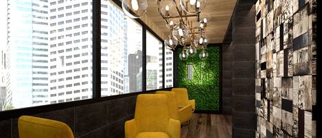 A modern interior with yellow chairs, a round table, and a green wall with a logo.