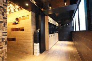 A modern reception area with wooden reception desk, a digital display, and a wall-mounted bike rack. - The Nap Tsim Sha Tsui (Kowloon)