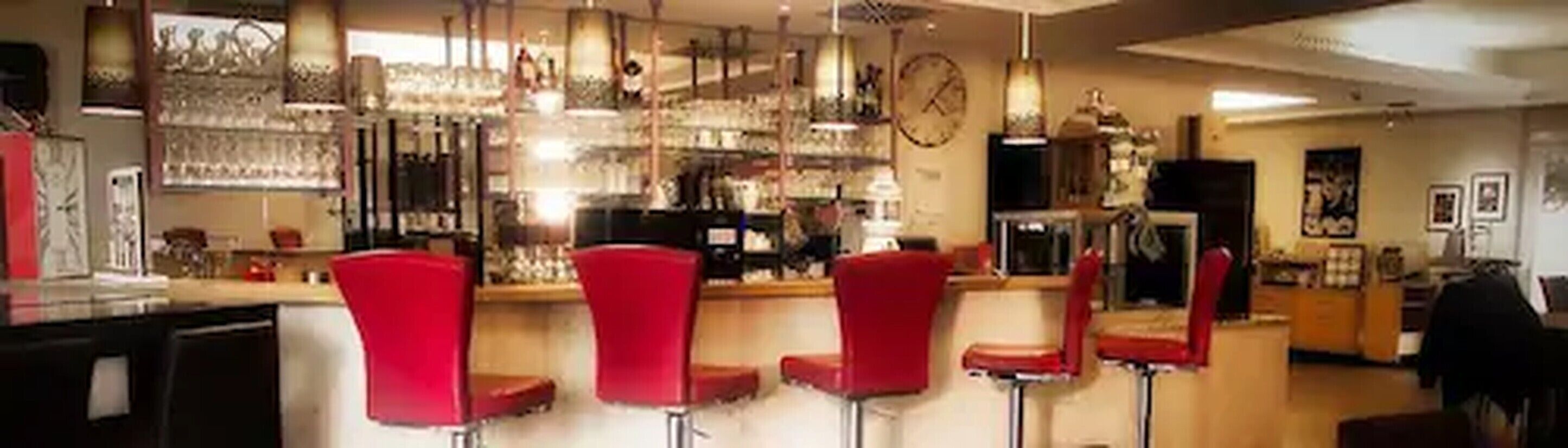 A bar area with red bar stools, a counter, and various bar items.