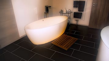 A modern bathroom with a freestanding bathtub, a towel rack, and a shower area.