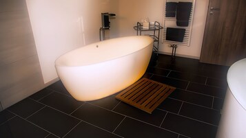 A modern bathroom with a freestanding bathtub, a towel rack, and a shower area.