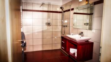 A modern bathroom with a glass shower enclosure, a vanity with a sink, and a large mirror.
