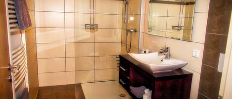 Une salle de bain moderne avec une douche à parois de verre, un meuble-lavabo et un grand miroir.