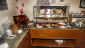 A buffet setup with various food items, including fruits, pastries, and a selection of meats. - Fritz Hotel (Weil am Rhein)