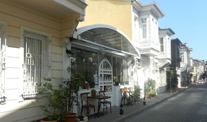 A street-side café with outdoor seating, potted plants, and a clear view of the street. - Royal Suites Sultanahmet (Istanbul)