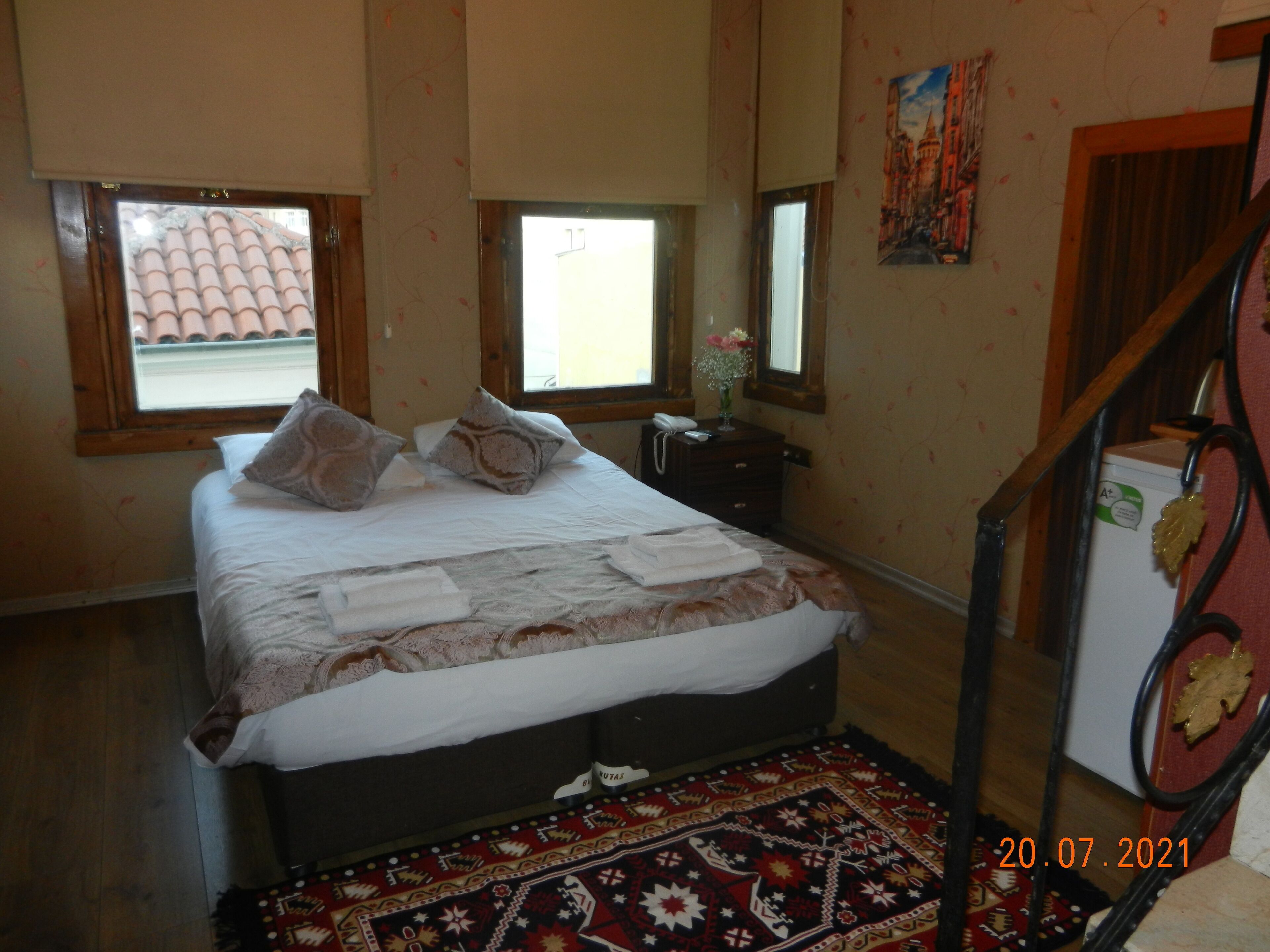 A bedroom with a bed, two windows, a dresser, a mirror, and a small refrigerator.