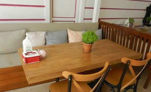 A dining area with a wooden table, four chairs, a potted plant, and a bottle of hand sanitizer. - Royal Suites Sultanahmet (Istanbul)
