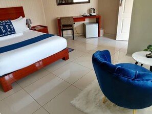 A hotel room with a large bed, a desk, a chair, and a small table. - Best Inn Hotel (Palapye)