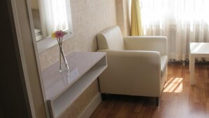 A modern living room with a sofa, a small table, and a mirror. - Idrisoglu Hotel (Kastamonu)