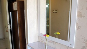 A bathroom with a white vanity, a mirror, and a vase with flowers. - Idrisoglu Hotel (Kastamonu)