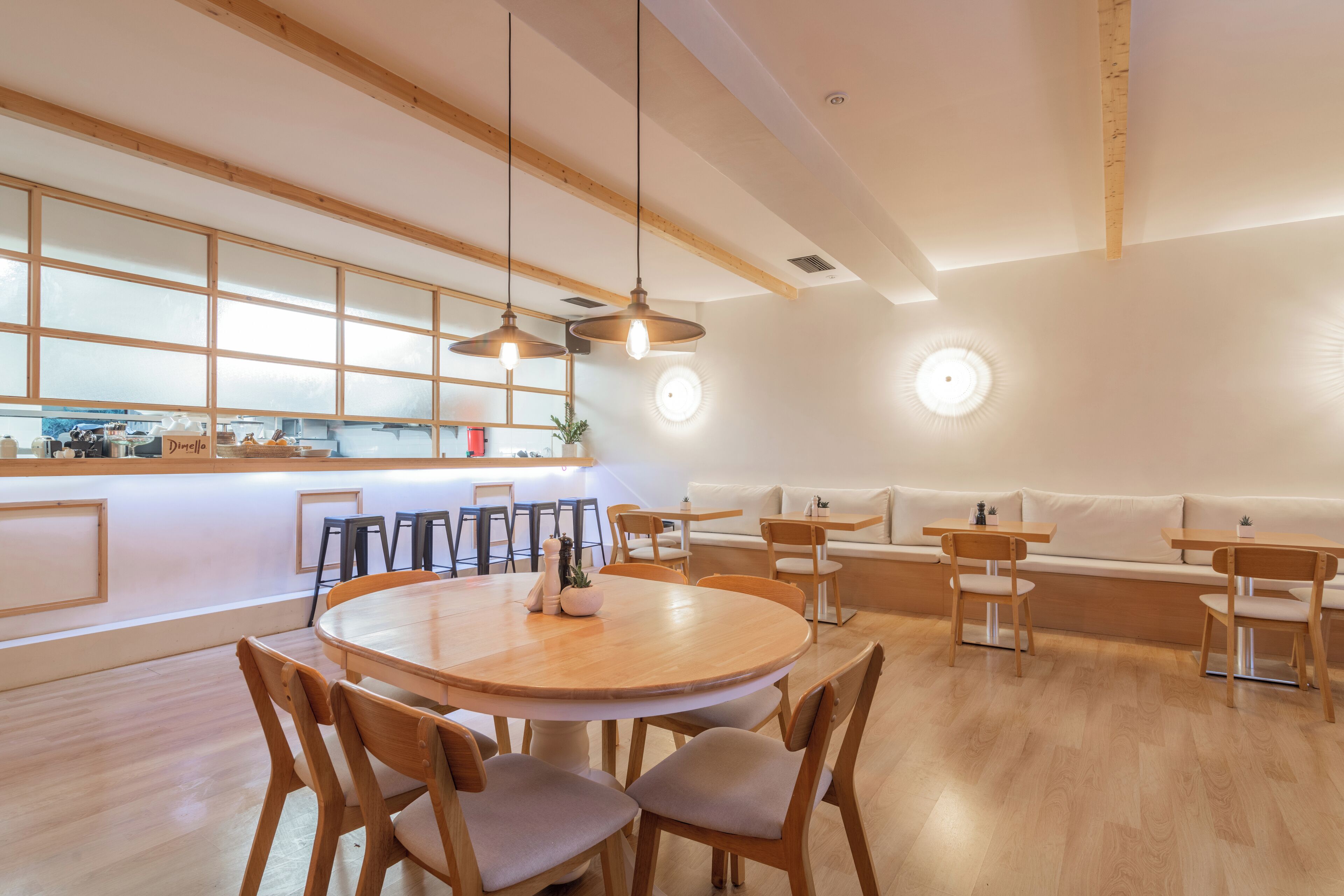A modern dining area with a round wooden table, cushioned chairs, and a long wooden bench.