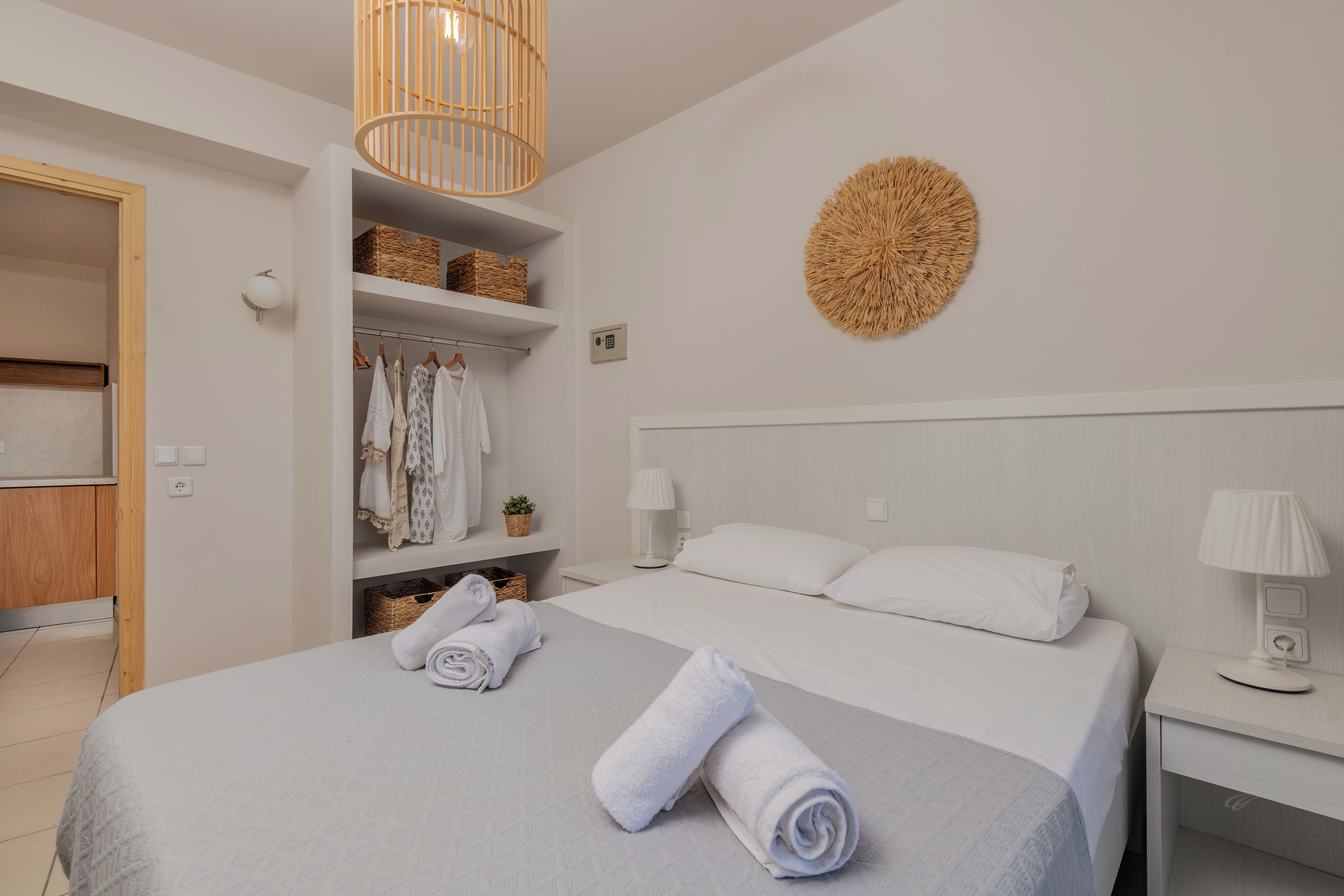 Un dormitorio ordenado con cama, mesitas de noche, un armario y una lámpara colgante.