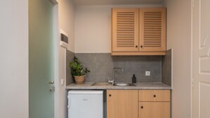 Une cuisine compacte avec des meubles de rangement en bois, un évier encastré et un petit réfrigérateur.