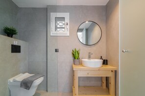 A modern bathroom with a toilet, a sink, a mirror, and a potted plant. - Alykes View Apartments (Zakynthos)