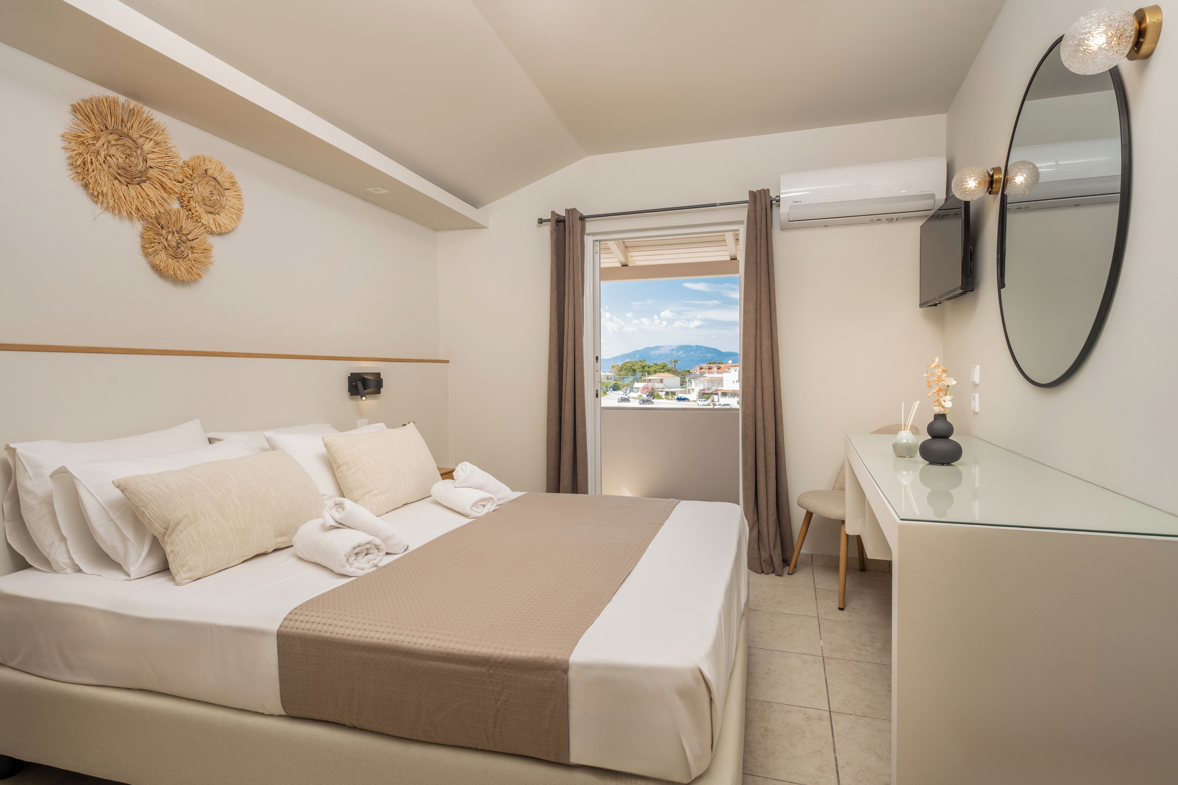 Une chambre d’hôtel avec un lit, un bureau, un miroir et une vue sur l’extérieur.