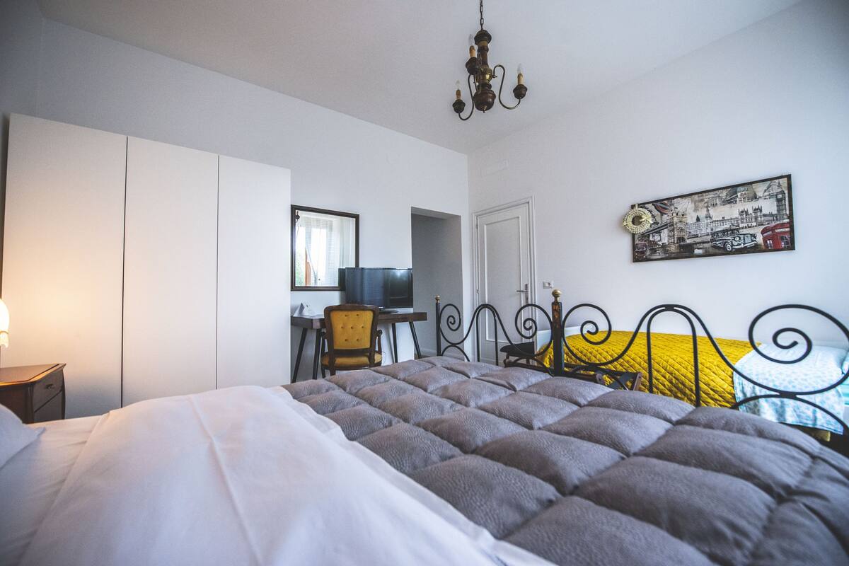 Une chambre à coucher avec un grand lit, un bureau, une chaise, une télévision et une porte.