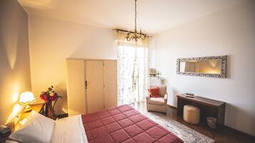 A bedroom with a bed, a nightstand, a lamp, a dresser, a chair, a mirror, and a rug.