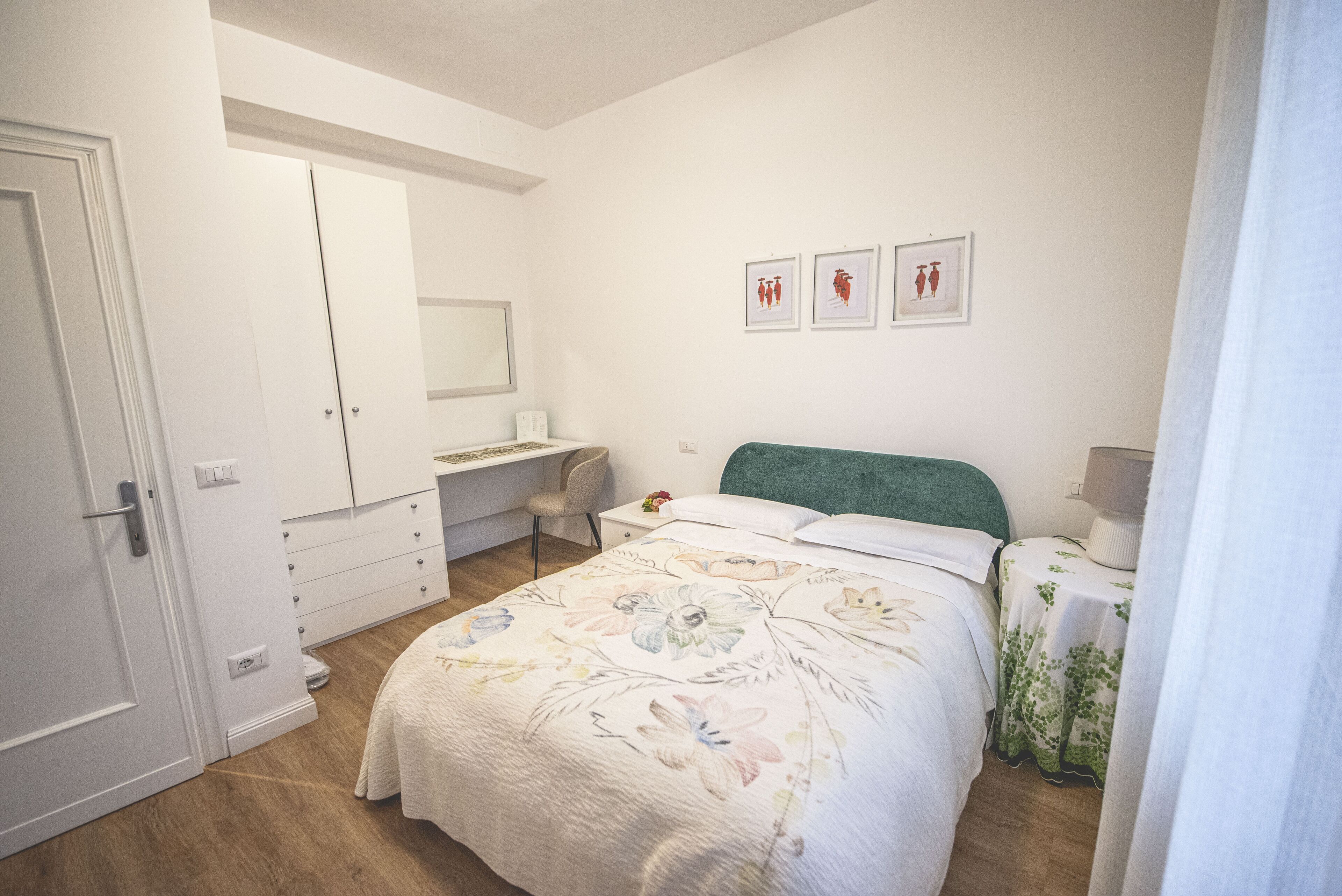 A bedroom with a bed, a desk, a chair, a wardrobe, and a mirror.