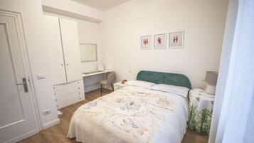 A bedroom with a bed, a desk, a chair, a wardrobe, and a mirror.