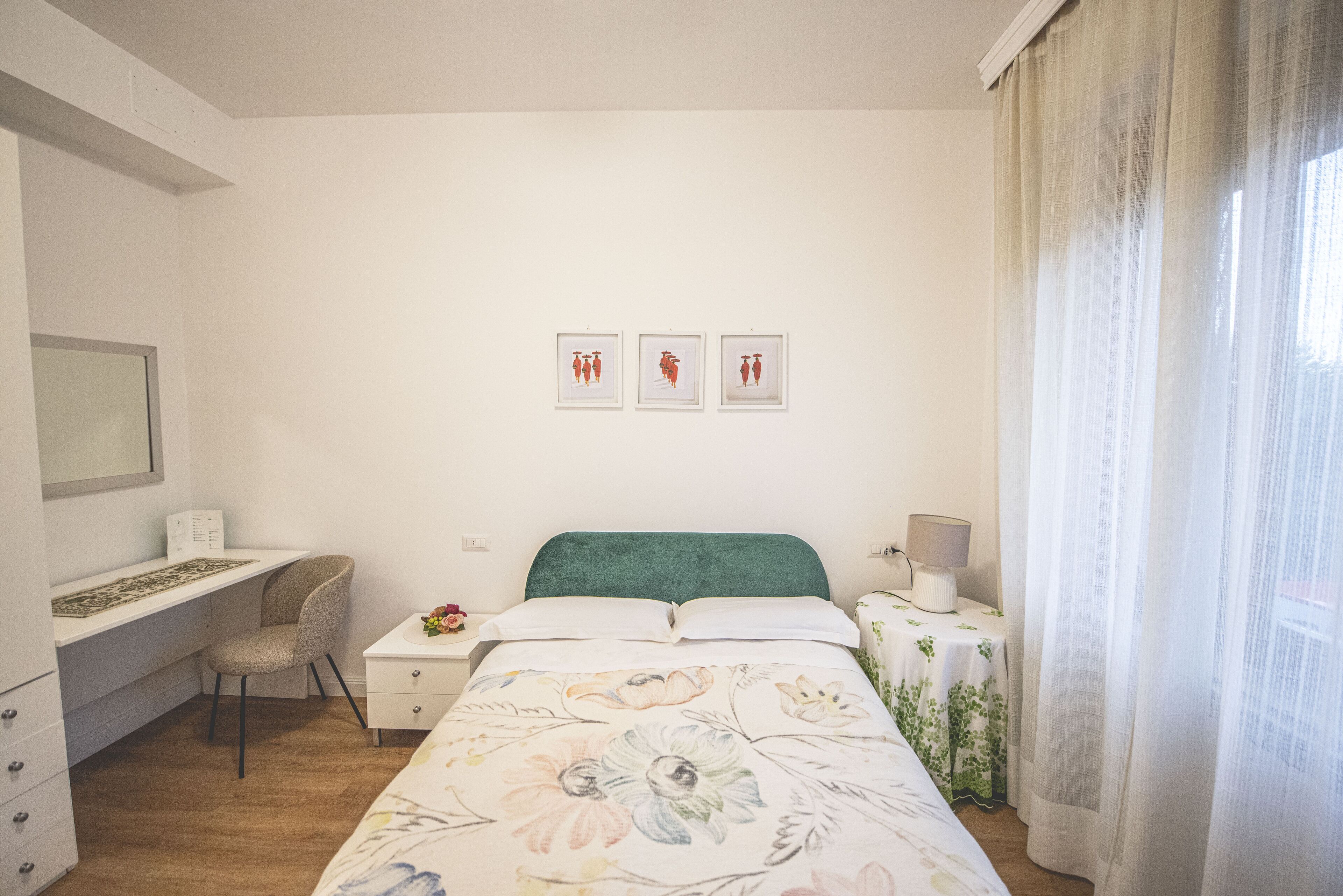Un dormitorio con cama, escritorio, silla y tres cuadros en la pared.