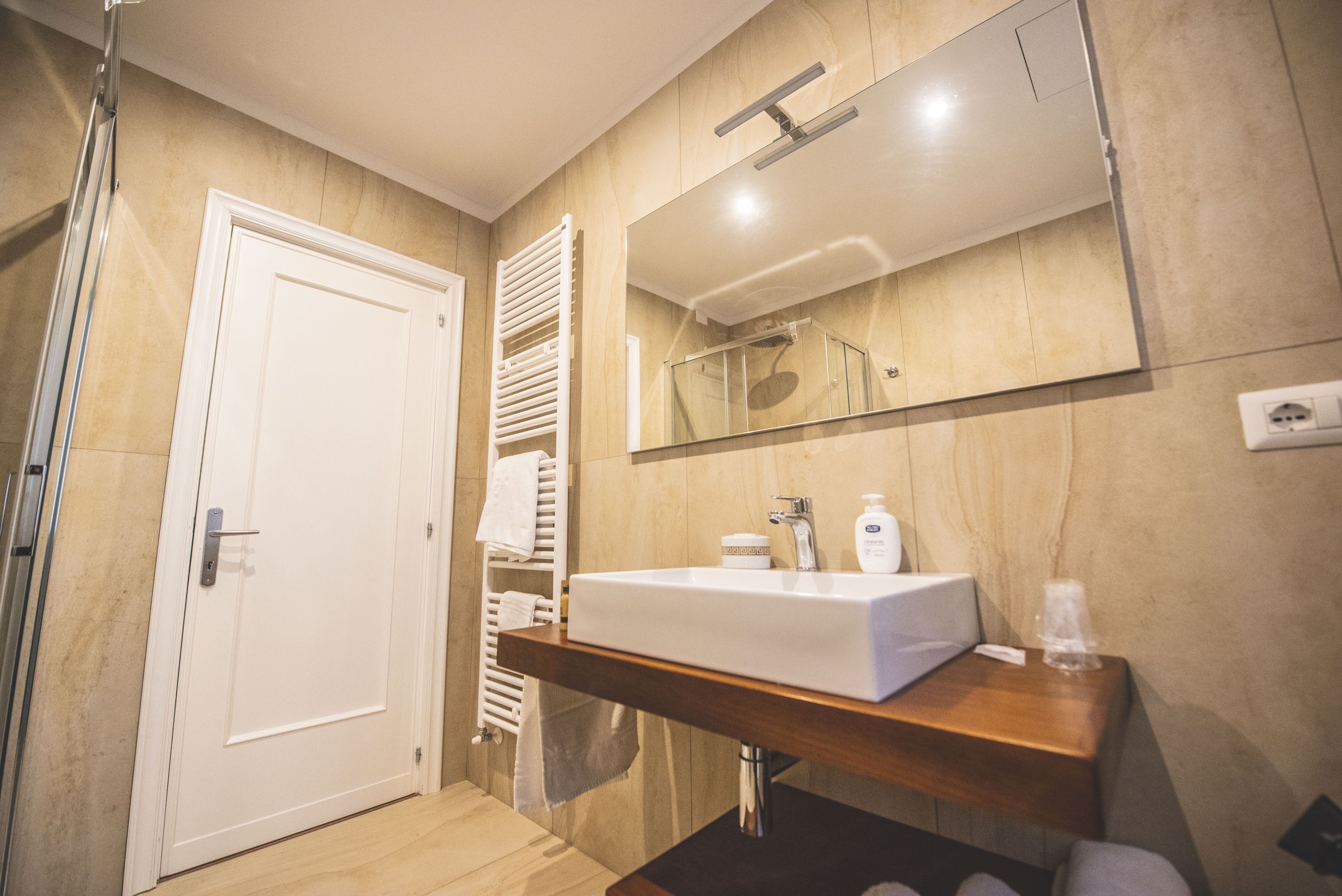 Une salle de bain moderne avec un meuble-lavabo en bois, un grand miroir et un espace douche.