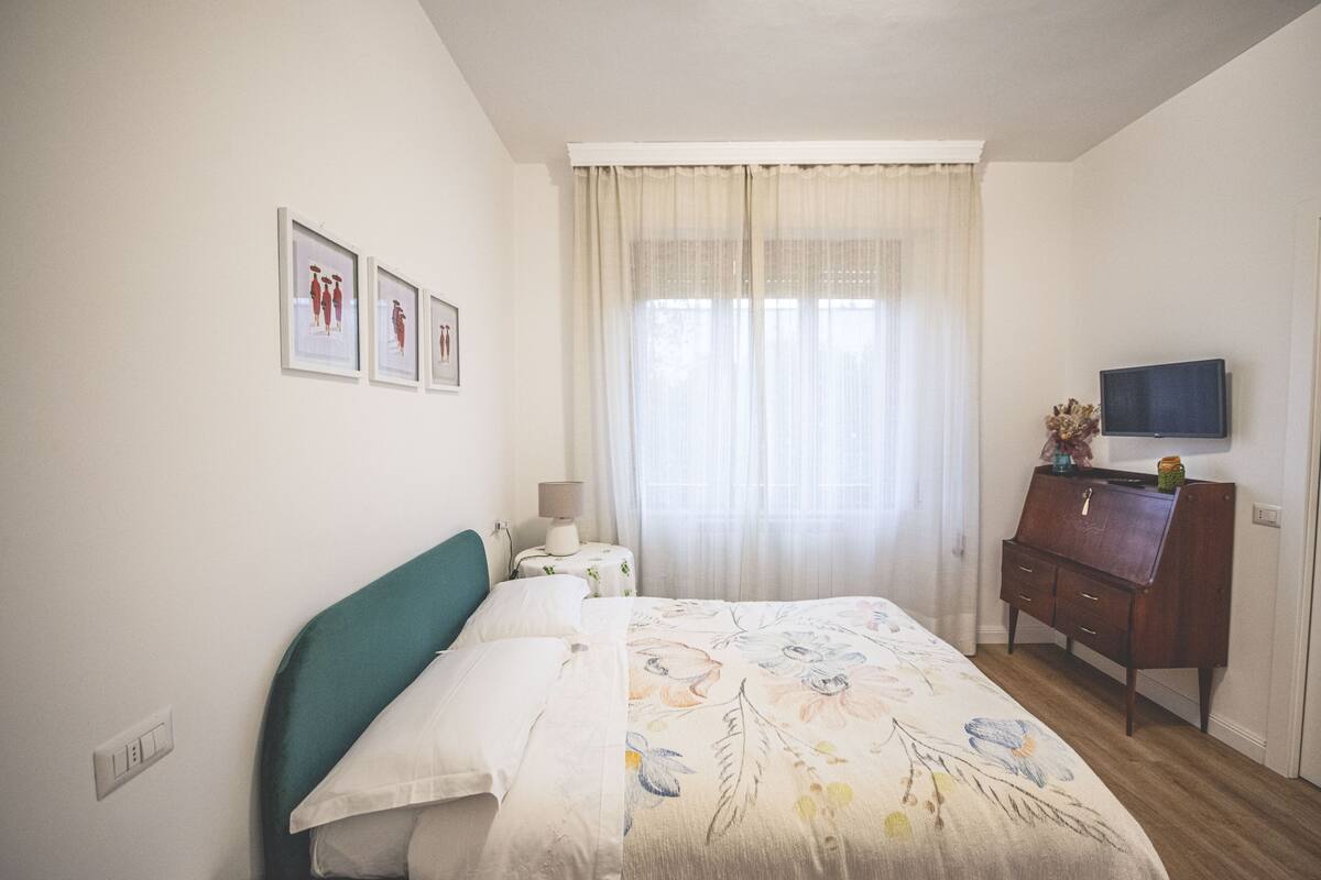 Une chambre à coucher avec un lit, une commode, un téléviseur et des tableaux encadrés accrochés au mur.