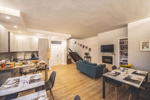 A modern kitchen with wooden cabinets and a dining area with a blue sofa and a table set for a meal. - B&B Il Girasole (Corciano)