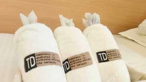 A bed with white pillows and a white pillowcase with a label that reads "TD Happiness is dedicated to everyone who lives seriously." - L'étoile de mer Tsim Sha Tsui (Kowloon)