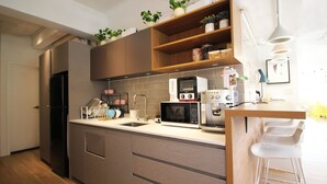 A modern kitchen with a built-in oven, microwave, and coffee maker. There are bar stools and a small bar area. - L'étoile de mer Tsim Sha Tsui (Kowloon)