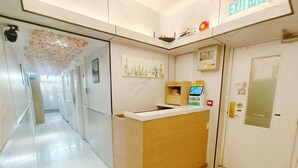 A hotel reception area with a wooden counter, a digital kiosk, and an exit sign. - L'étoile de mer Tsim Sha Tsui (Kowloon)