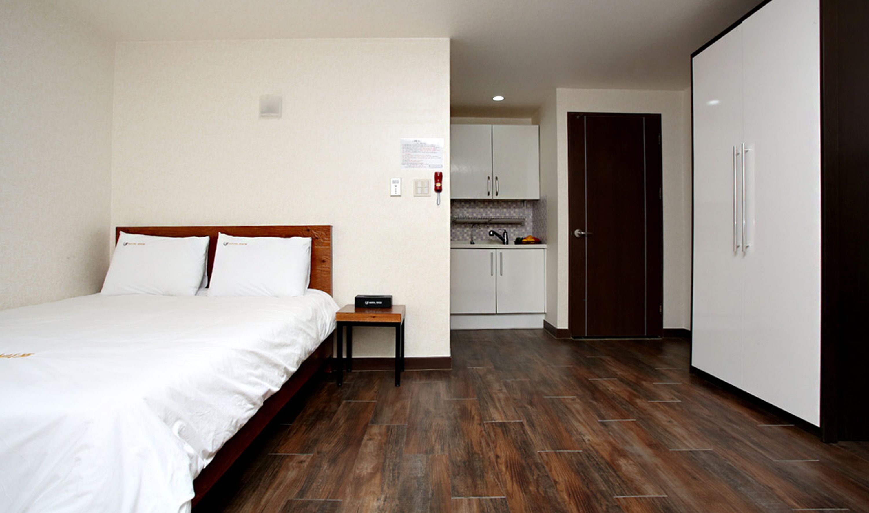 Habitación de hotel con cama, una mesita, kitchenette y armario.