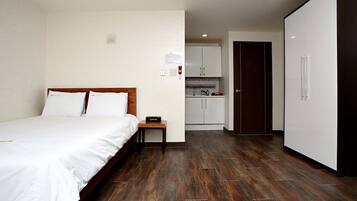 Habitación de hotel con cama, una mesita, kitchenette y armario.