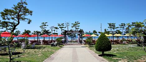 A paved pathway leading to beach umbrellas and beach chairs.