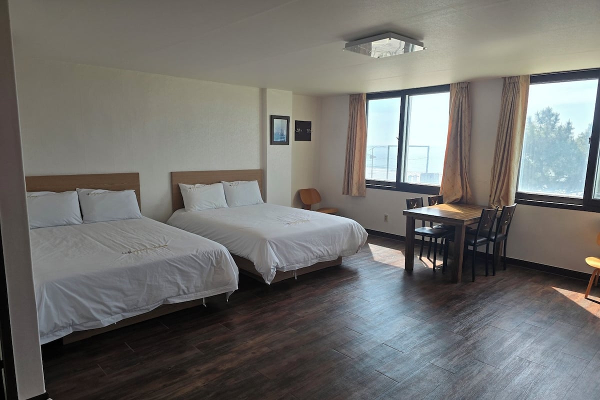 Una habitación de hotel con dos camas, una mesita y una silla.