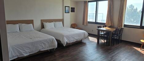 Una habitación de hotel con dos camas, una mesita y una silla.