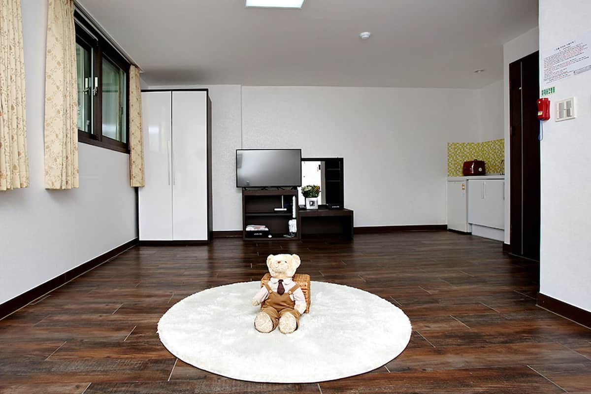 Una sala de estar moderna con un ventanal grande, un televisor de pantalla plana y un oso de peluche sobre una alfombra.