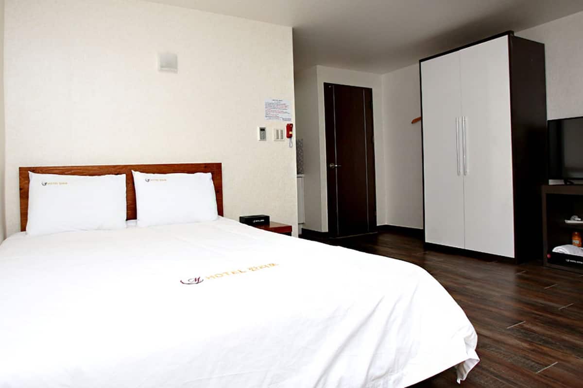 Una habitación de hotel con cama, armario, escritorio y televisor.