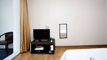 Een hotelkamer met een bed, een televisie op een standaard, een spiegel aan de muur en een stoel.