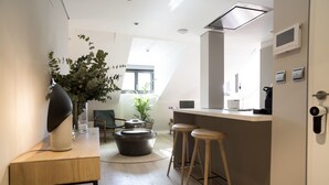 Eine moderne Küche mit Bar, Holzstühlen und einer großen Kübelpflanze.